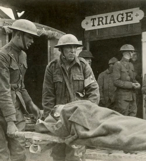 World War I medics carry an injured soldier on a stretcher to a triage station of the U.S. Army 42nd Division near Suippes, France, 1918.