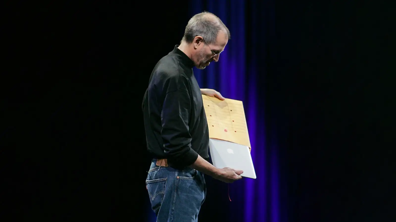Steve Jobs holding a manila envelope with the first MacBook Air inside during Apple’s 2008 keynote presentation, showcasing the world’s thinnest laptop.