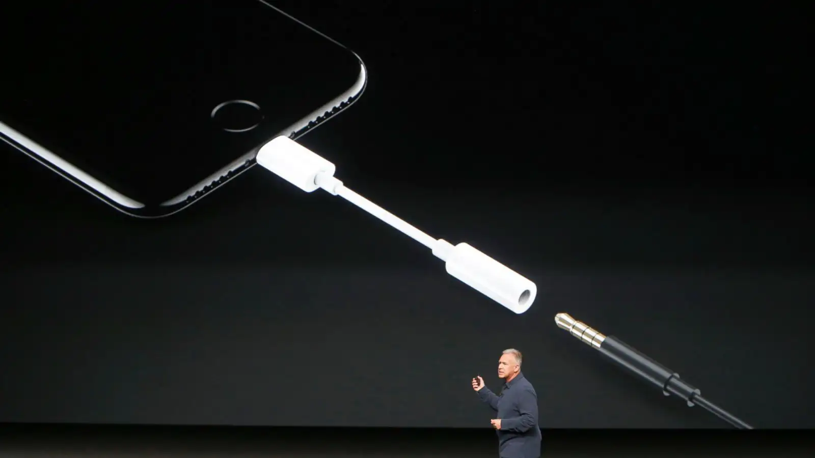 Apple presentation showing the iPhone 7 Lightning adapter replacing the traditional 3.5mm headphone jack, highlighting the removal of the headphone port in 2016.