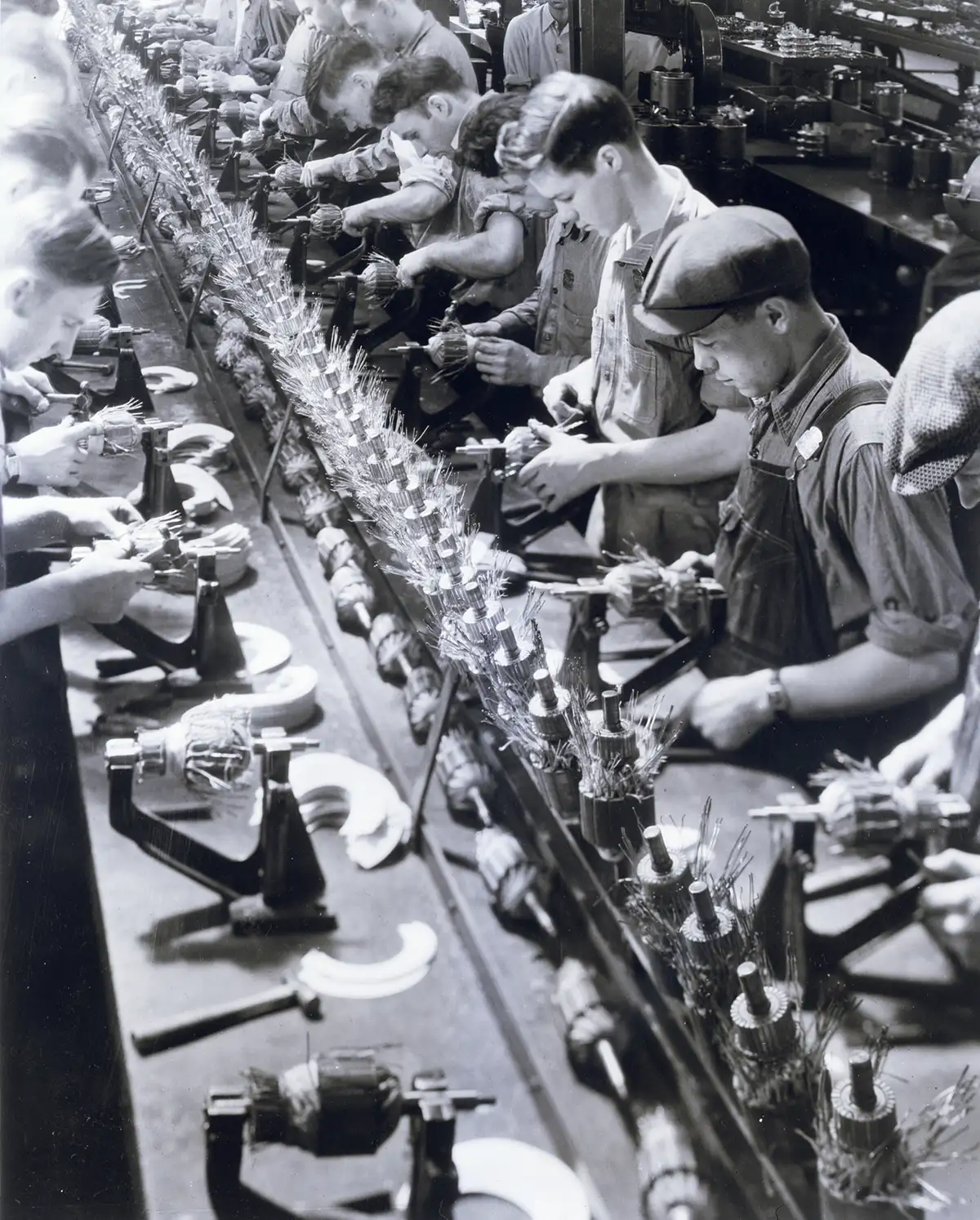 Historic image of factory workers on an assembly line, illustrating early industrial workflow fragmentation and task specialization.