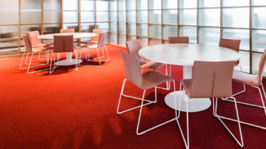 Vergaderzaal met witte stoelen en rood tapijt