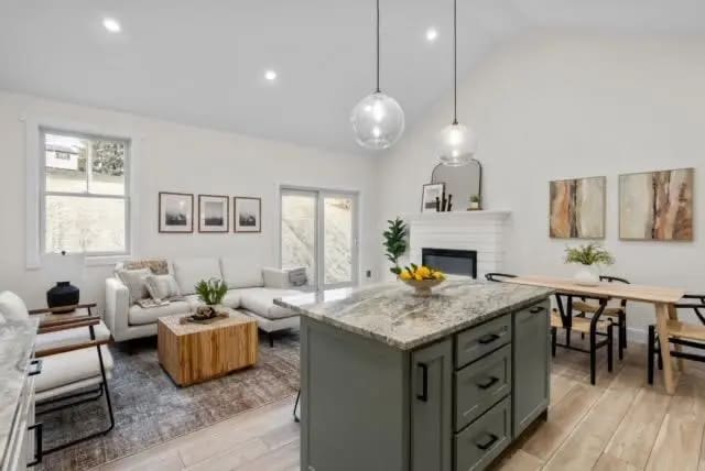 a large open concept living room and dining room with white walls and wood flooring and a large kitchen island