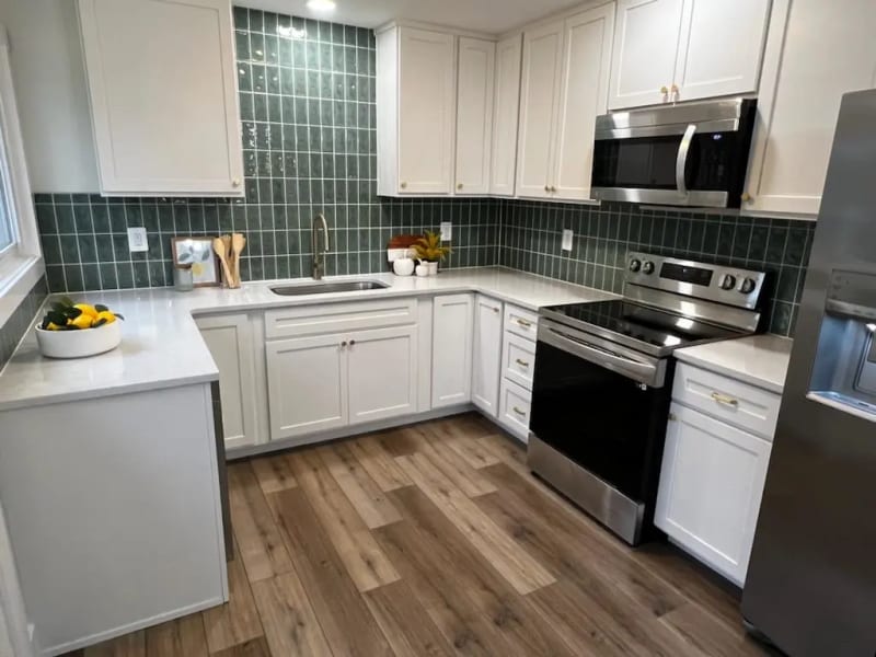 a kitchen with white cabinets, black and silver stove top oven, and a dishwasher