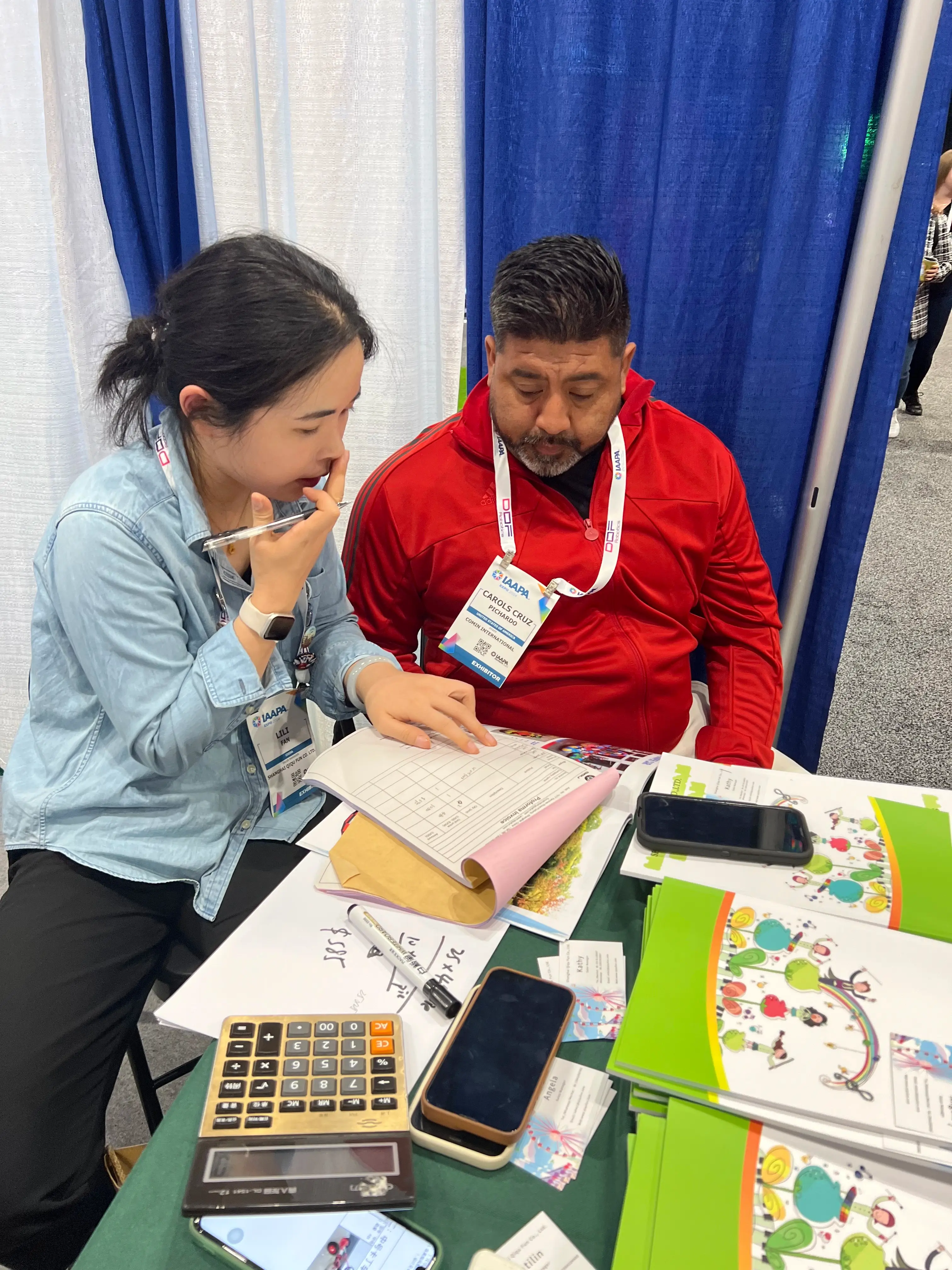 Shanghai Qiqu Fun expert finalizing commercial amusement ride fleet contract details with a North American park operator at IAAPA Expo Orlando 2024