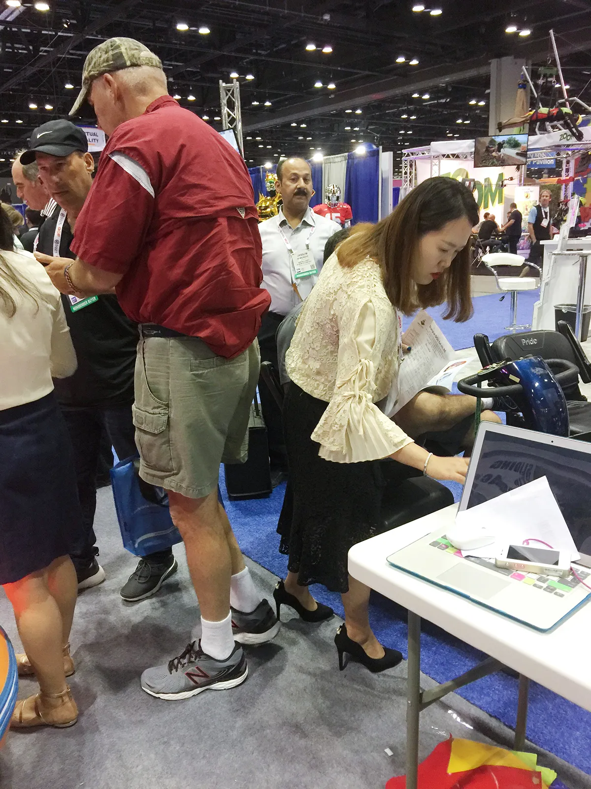 Shanghai Qiqu Fun Founder Emily managing back-to-back fleet inquiries and on-site quotes for heavy-duty amusement rides at a crowded IAAPA Expo Orlando 2017 booth