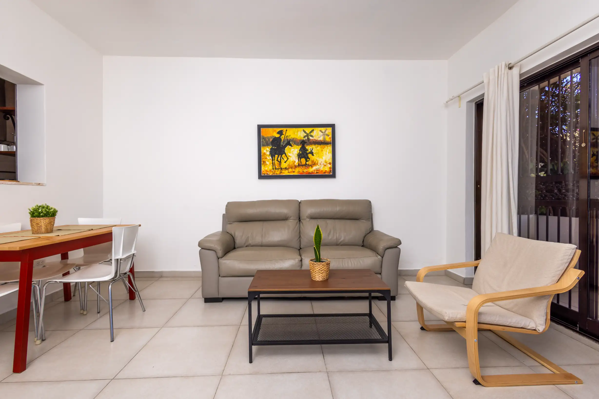 Open living-dining area with Don Quixote artwork and four-seat dining table — Unidad 2B