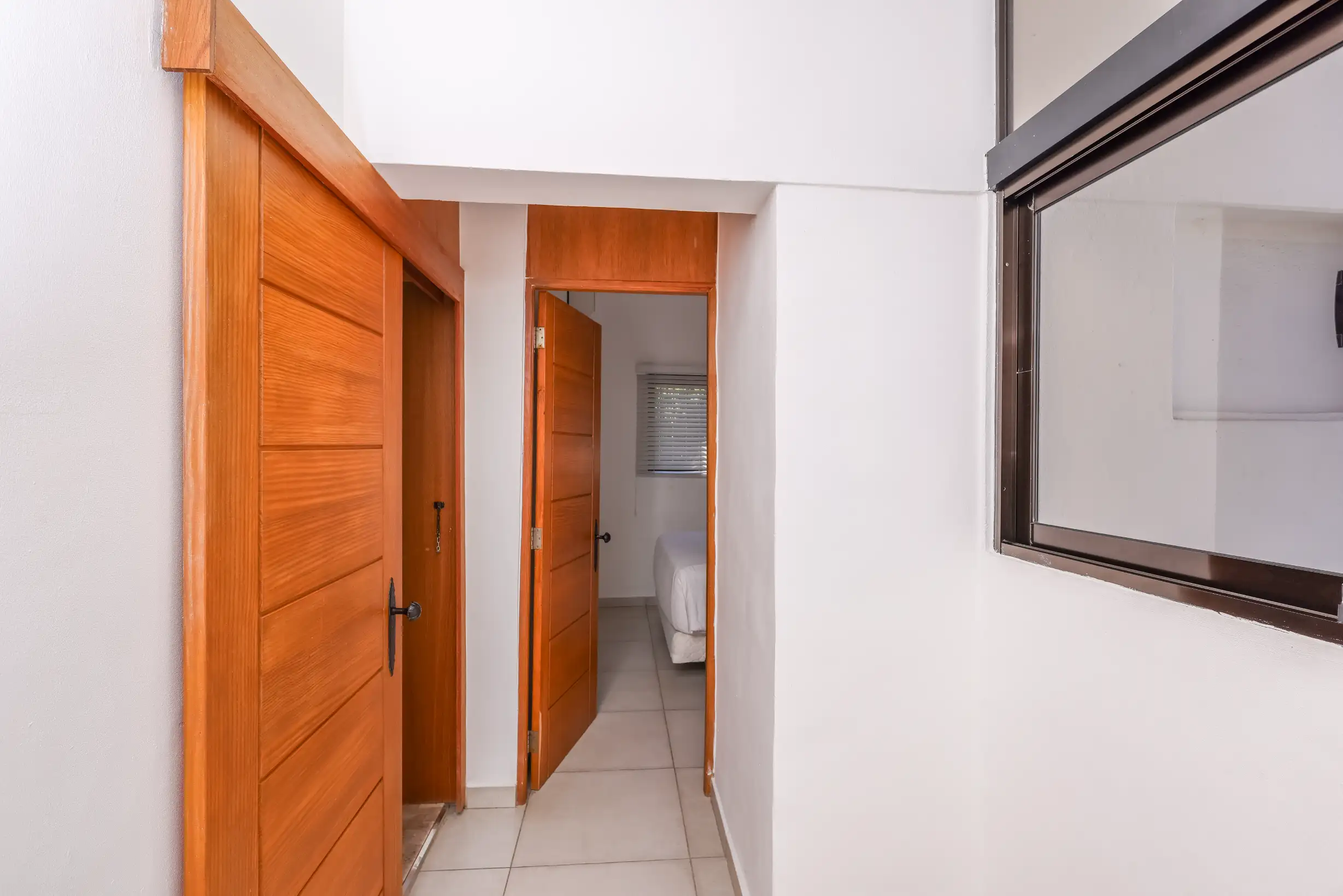 Hallway with tropical-wood doors leading to the bedrooms — Unidad 3B