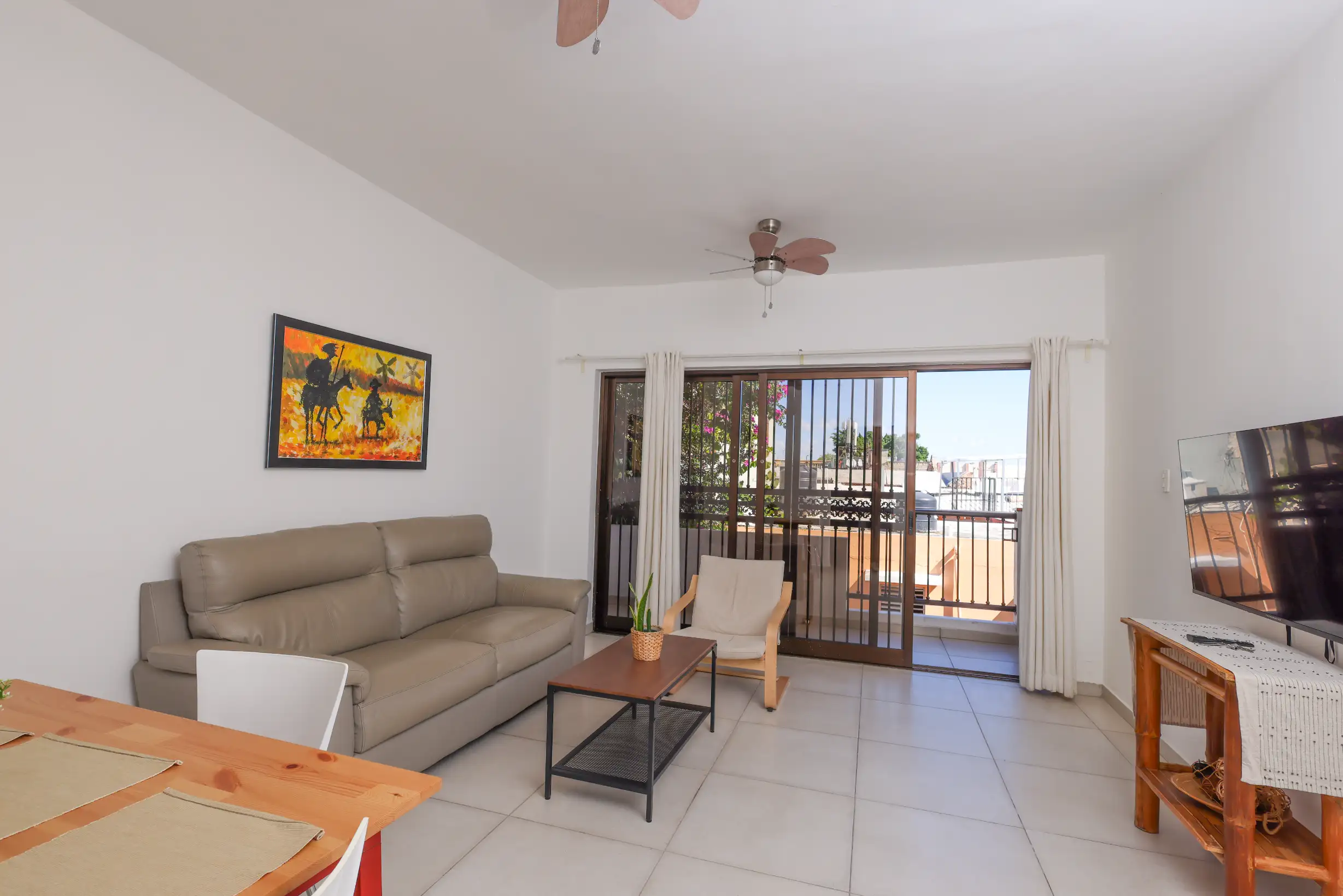 Living room with balcony open to the Colonial Zone framed by bougainvillea — Unidad 3B