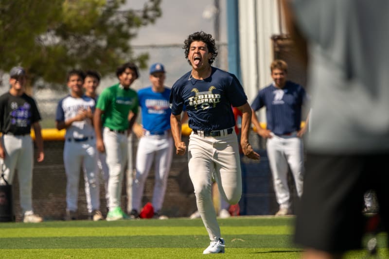 A player celebrating as he runs across the field while his teammates look on