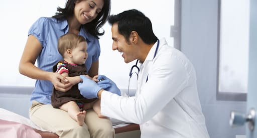 A doctor playing with the baby. The Happy Sleeper offers one-on-one consultations