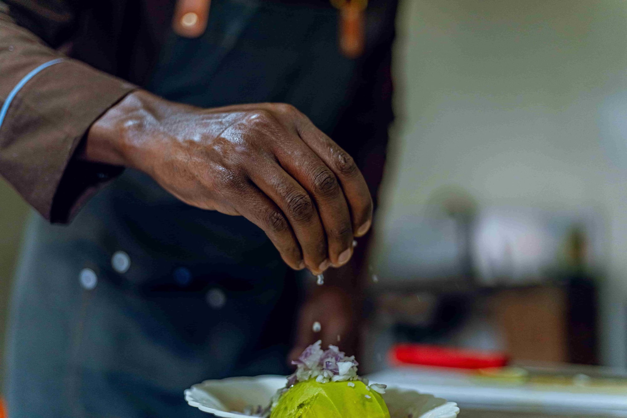 Close-up of a chef seasoning an avocado dish, adding a touch of culinary art to gourmet cooking.