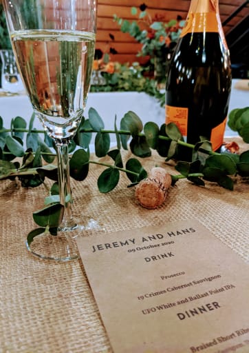 A full champange glass and open bottle sit on the table next to the dinner menu.