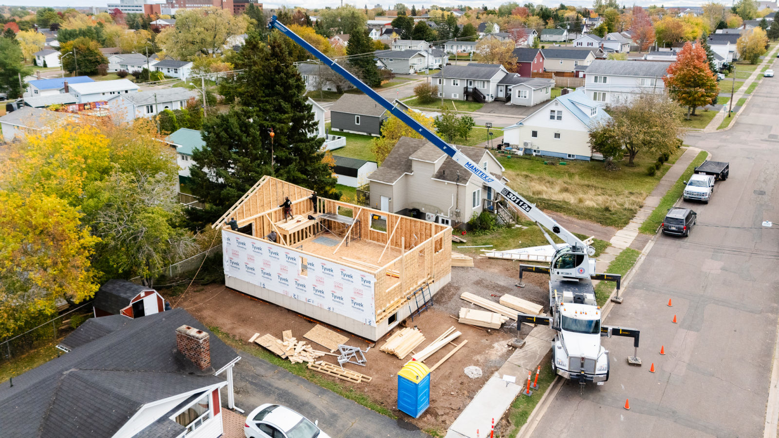 Aerial drone view of J.A. Kelly crew unloading roof trusses on a new home framing project in Moncton NB