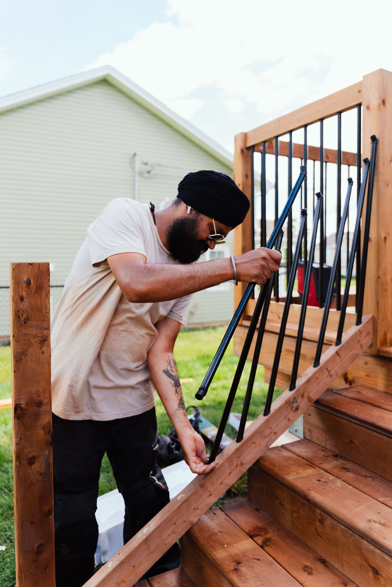 J.A. Kelly carpenter fitting black aluminum stair balusters on the finished deck staircase in Dieppe, NB