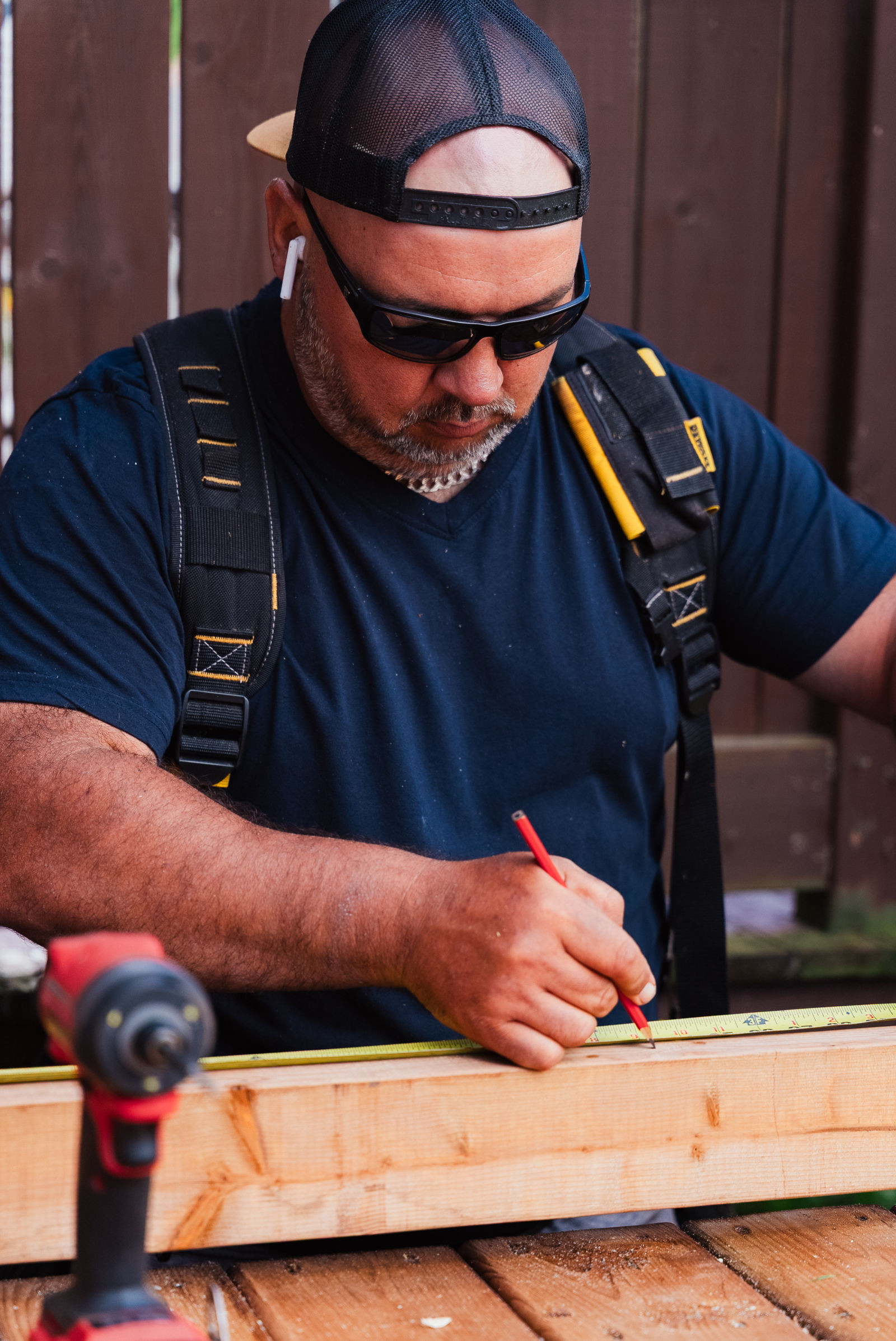 J.A. Kelly crew member measuring and marking a deck board with a pencil and tape measure in Dieppe, NB