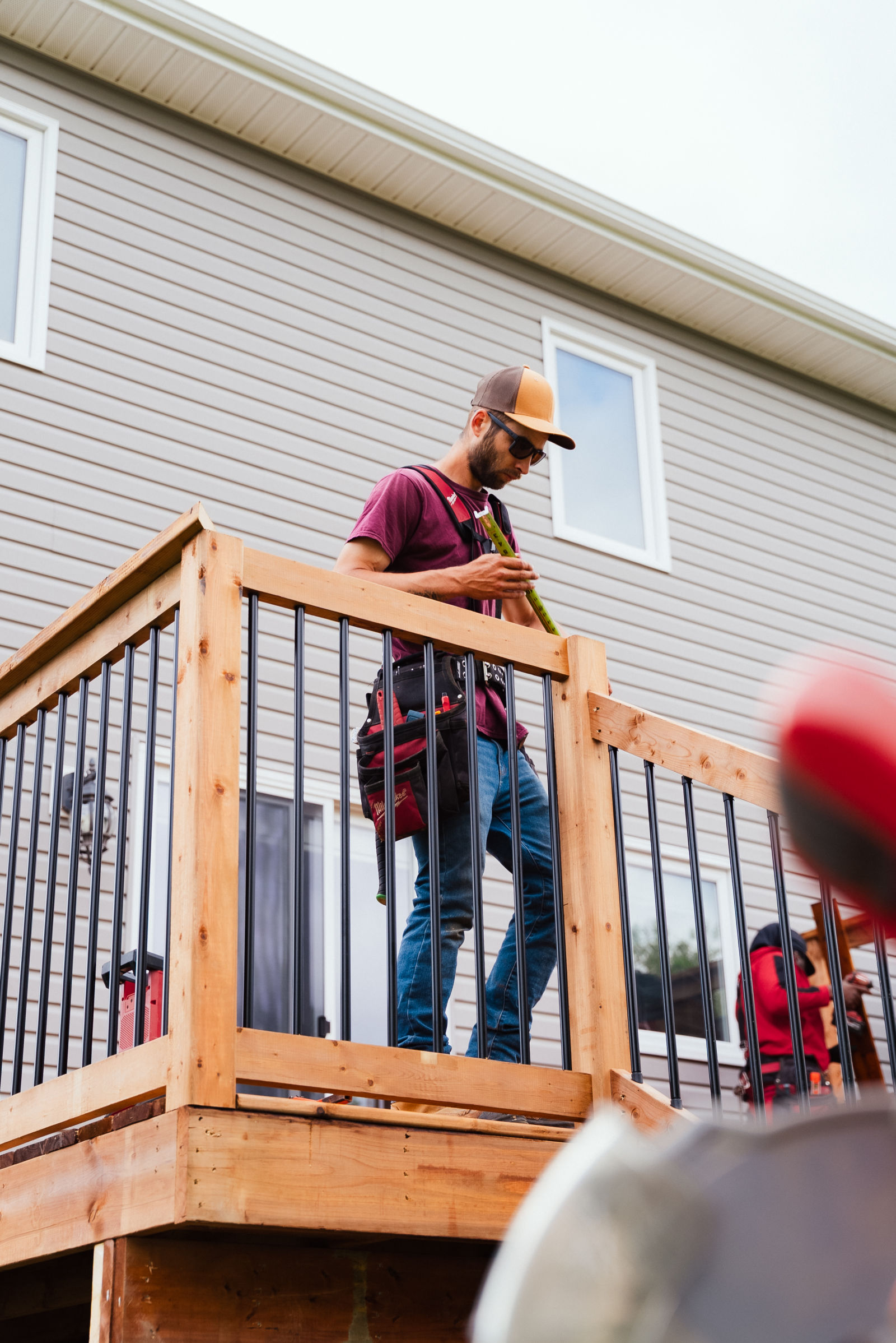 J.A. Kelly carpenter installing black aluminum balusters on the new deck railing in Dieppe, NB