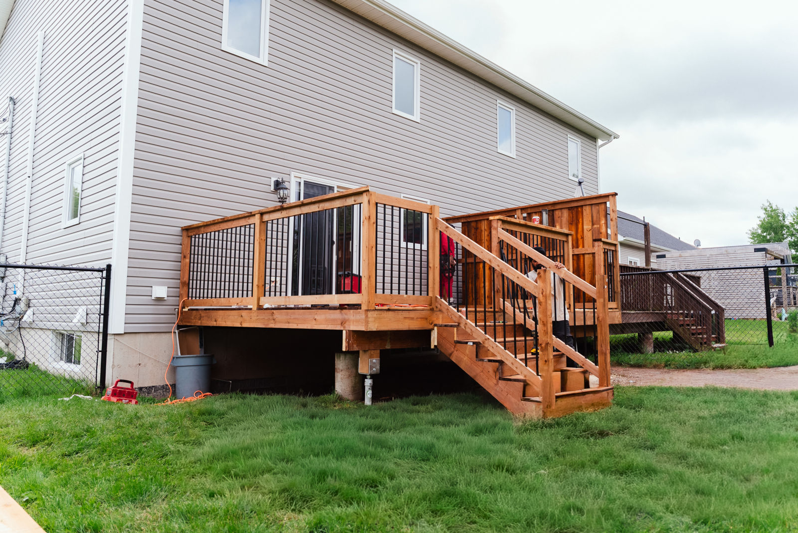 Finished raised pressure-treated deck with black aluminum railings and a staircase, built by J.A. Kelly Contracting on Lorette St in Dieppe, NB