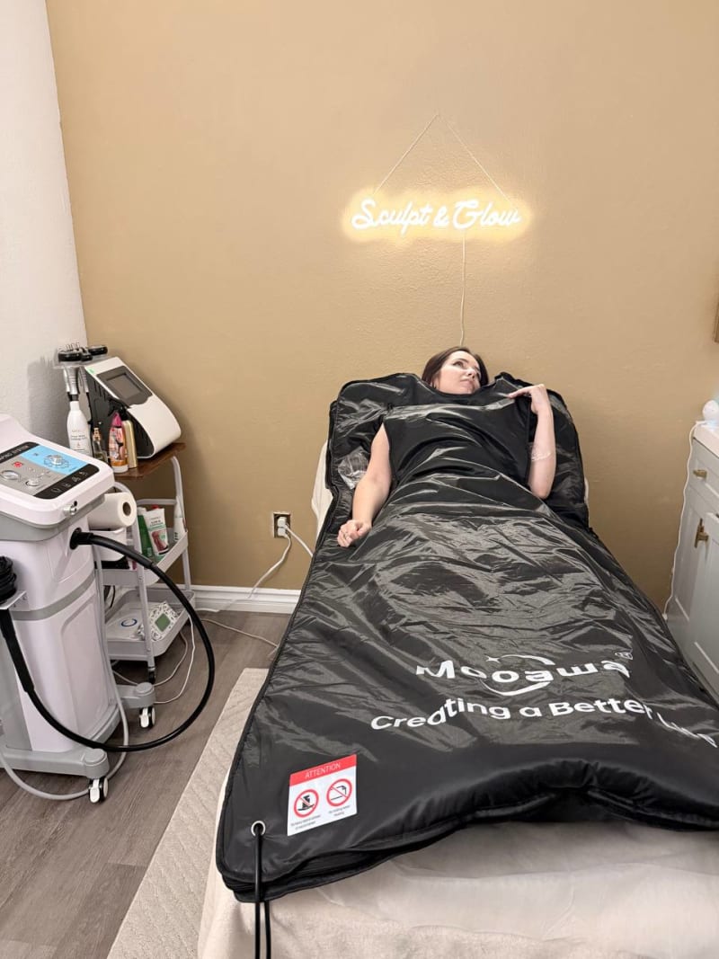 Client in sauna blanket Sculpt and Glow San Diego neon sign