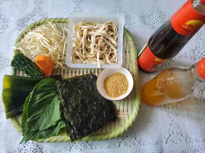 쟁반에 놓인 면·콩나물·다시마·깻잎·김·깨소금과 양념병