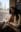 A woman in a blazer and skirt sits on a train, looking at the viewer with a slight smile. blurred out low res