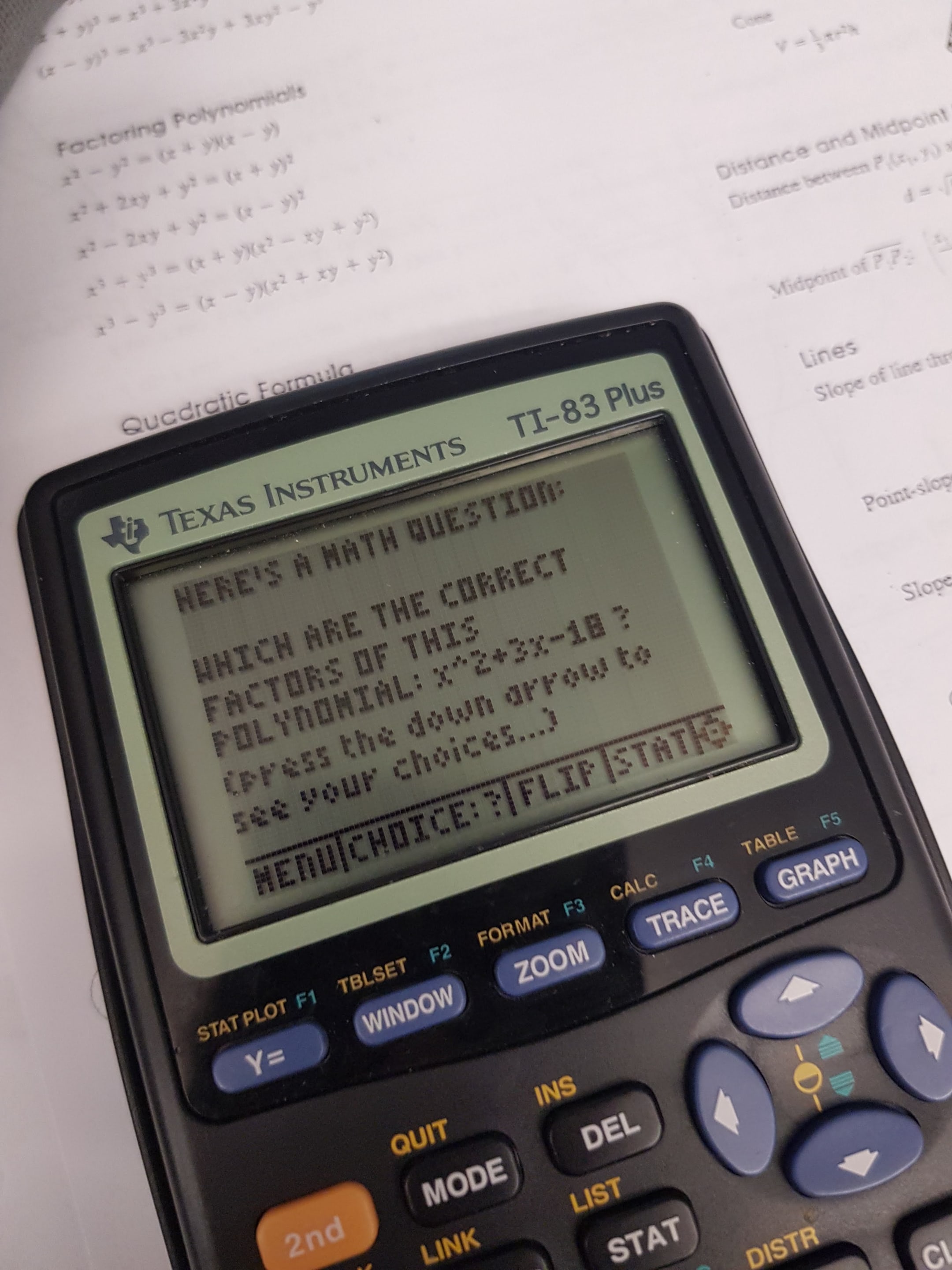 A close-up photograph of a TI-83 Plus calculator displaying a math problem. The image captures the calculator's screen and buttons alongside printed equations.