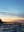 A silhouetted figure stands on a beach at sunset, with the sky reflecting off the wet sand. The image captures a moment of solitude and tranquility. blurred out low res