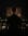 A figure stands before a display of photos and candles. The scene evokes a sense of loss, reflection, and remembrance. blurred out low res