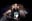 This image depicts a theatrical scene from the musical '13'. A young man is flanked by two women, all interacting in a humorous and expressive manner. blurred out low res