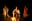 Three figures are gathered around a campfire in a dark, outdoor setting. The lighting is dramatic, with the fire casting a warm glow on the subjects and the surrounding environment. blurred out low res