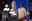 A young man in a colorful hoodie stands confidently on a city street at dusk, surrounded by blurred lights. blurred out low res