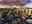 An aerial view of a cityscape with a dramatic sky. The image captures a bustling urban environment bathed in the warm light of sunset. blurred out low res