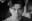 A black and white close-up portrait of a young Asian man. The image focuses on his face, capturing his contemplative gaze. blurred out low res