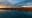 A tranquil landscape captures the vibrant colors of autumn reflected in the calm water. The sky is filled with dramatic clouds, creating a stunning contrast with the water's stillness. blurred out low res