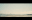 A tranquil coastal scene featuring a cityscape in the distance under a soft, pastel sky. A dog is running across the beach. blurred out low res