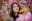 A young woman gazes upward amidst a vibrant display of pink cherry blossoms, bathed in soft, natural light. The composition highlights the interplay of the subject's expression and the surrounding floral beauty. blurred out low res