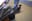 A pigeon in flight, captured against a textured building facade. The image captures the dynamic movement and the details of the bird's feathers. blurred out low res