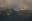 A seaplane soars against a backdrop of towering, snow-dusted mountains. The scene is enveloped in the soft light of a cloudy day. blurred out low res