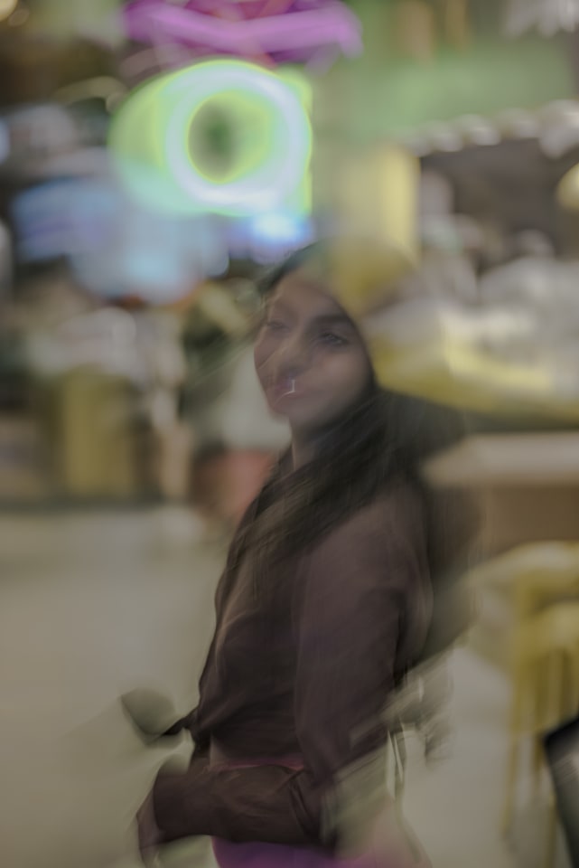 An abstract portrait of a woman is captured through a dreamy lens, where colors blend and blur to create a sense of movement and emotion.