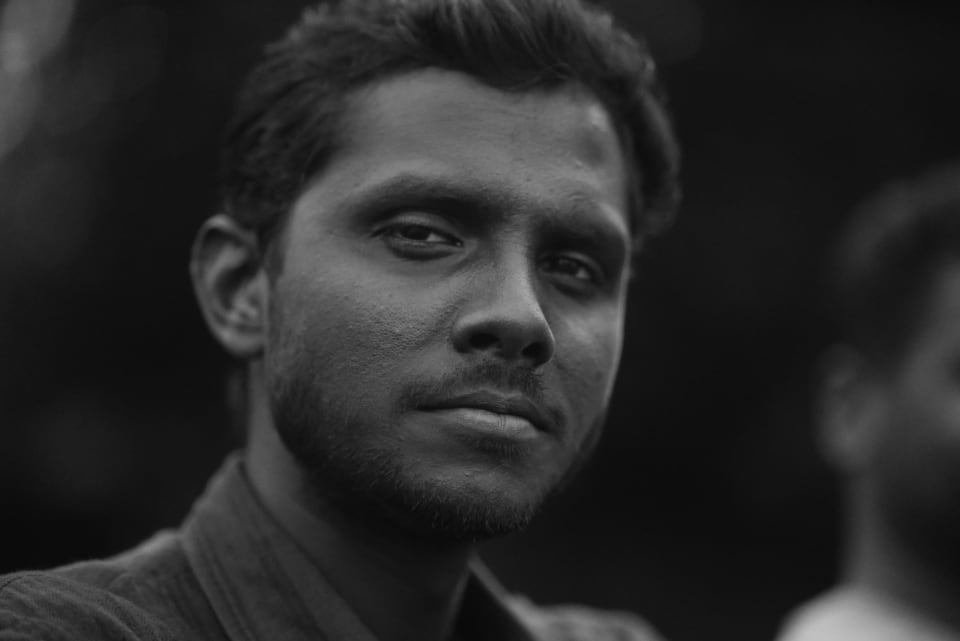 A black and white portrait of a man, showcasing a close-up of his face and expression. The image captures a mood of introspection.
