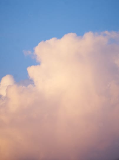 A photograph of a cloud formation in the sky. The cloud has a soft, pastel color.