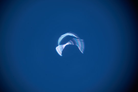 A pale blue and purple ribbon of light crosses a dark blue field.