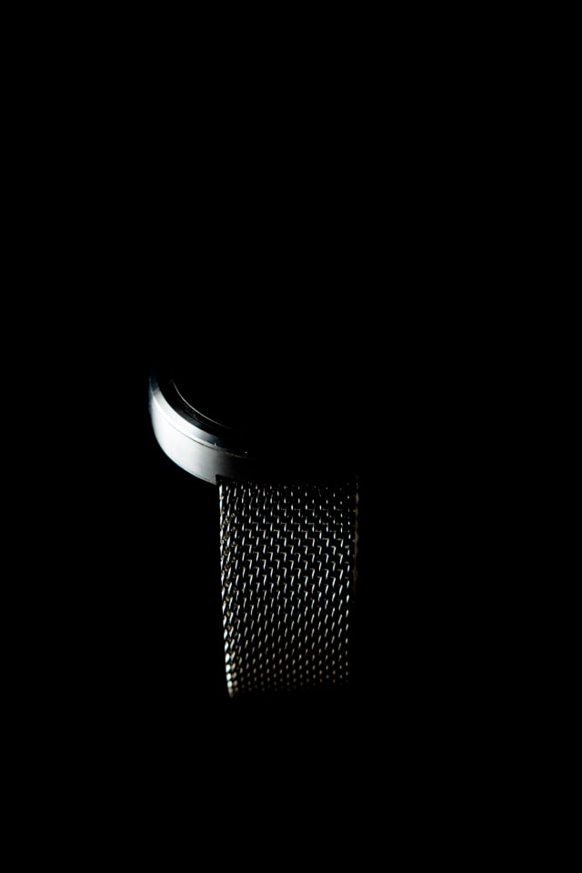 A close view of a silver mesh band against black.