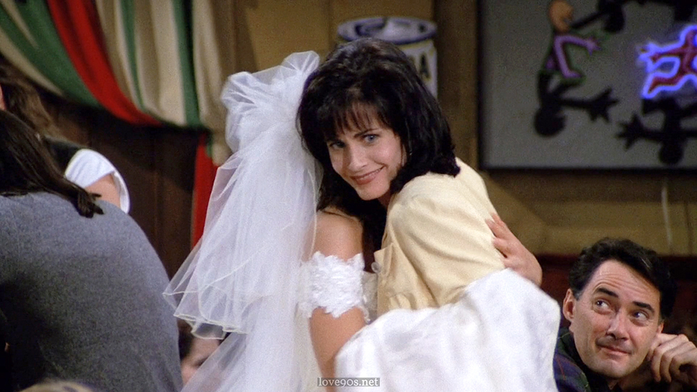 Monica in pale yellow jacket and white ribbed tee at Central Perk, Friends S1E1