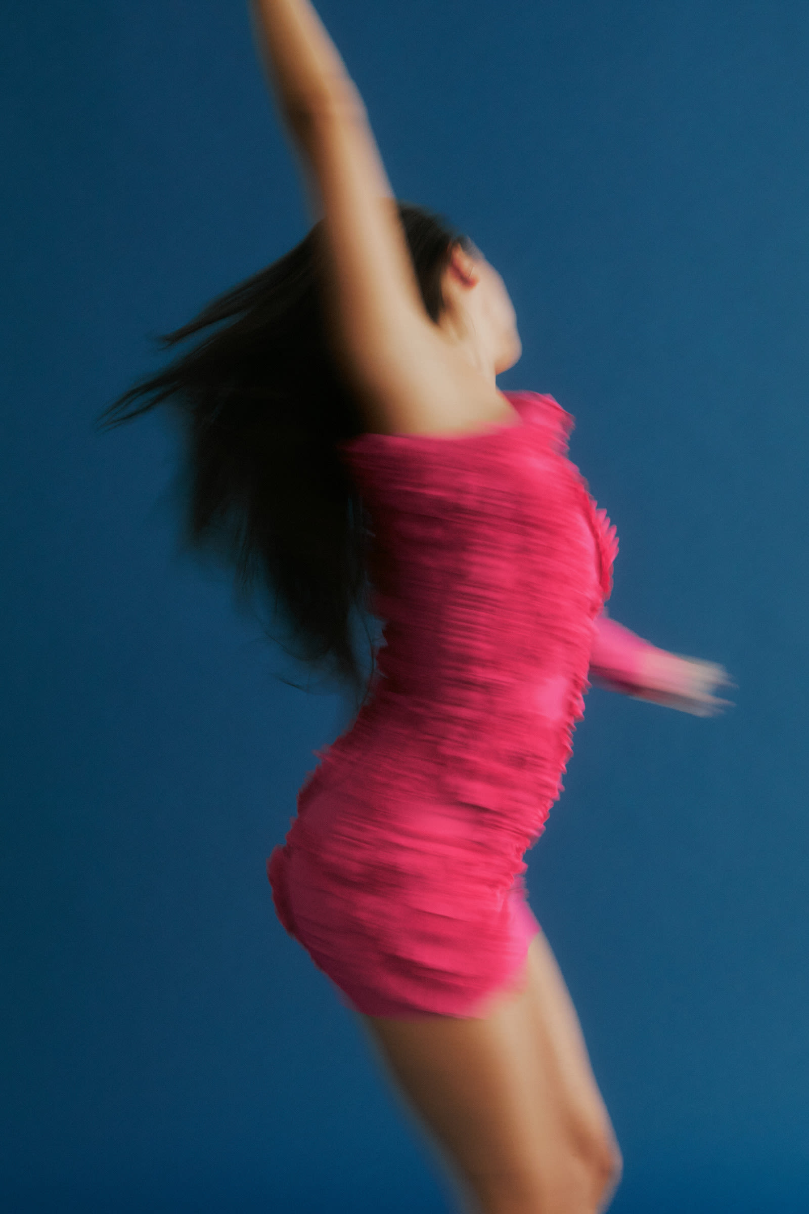 A woman leaping joyfully against a blue backdrop