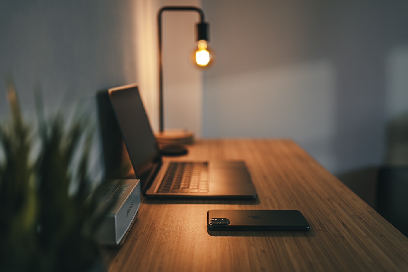 A warm, clean home desk with a laptop and lamp