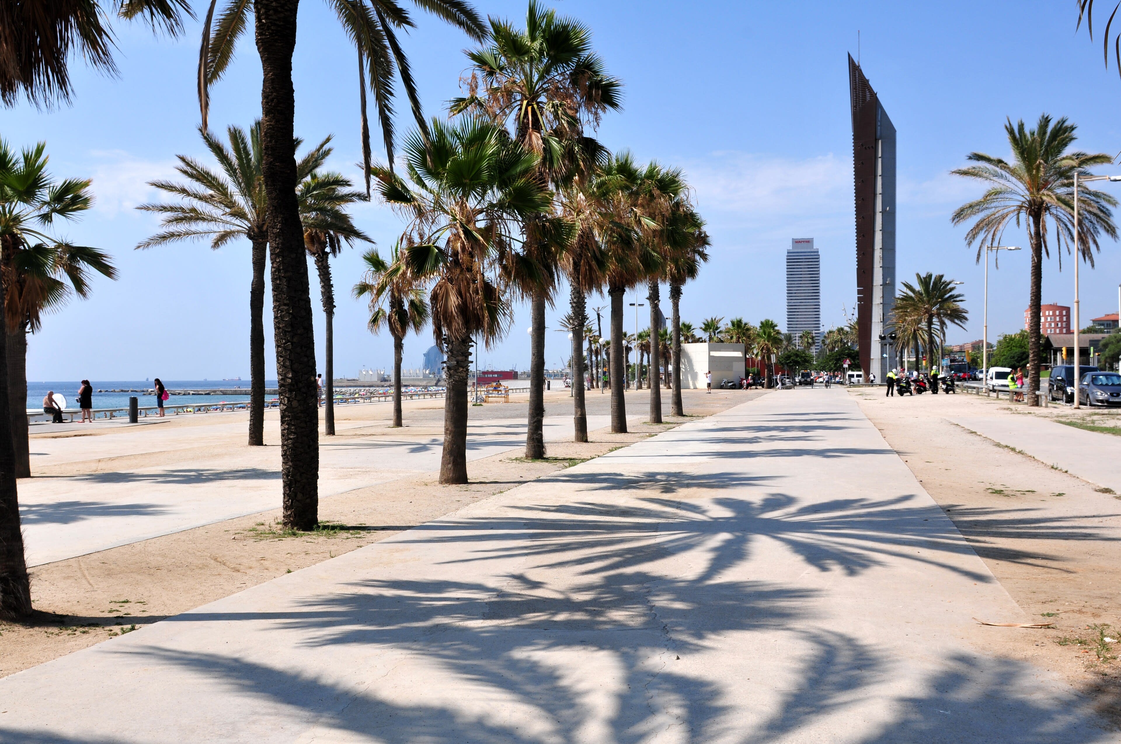 A sweeping Barcelona beach scene — sand, the boardwalk, swimmers, the city behind
