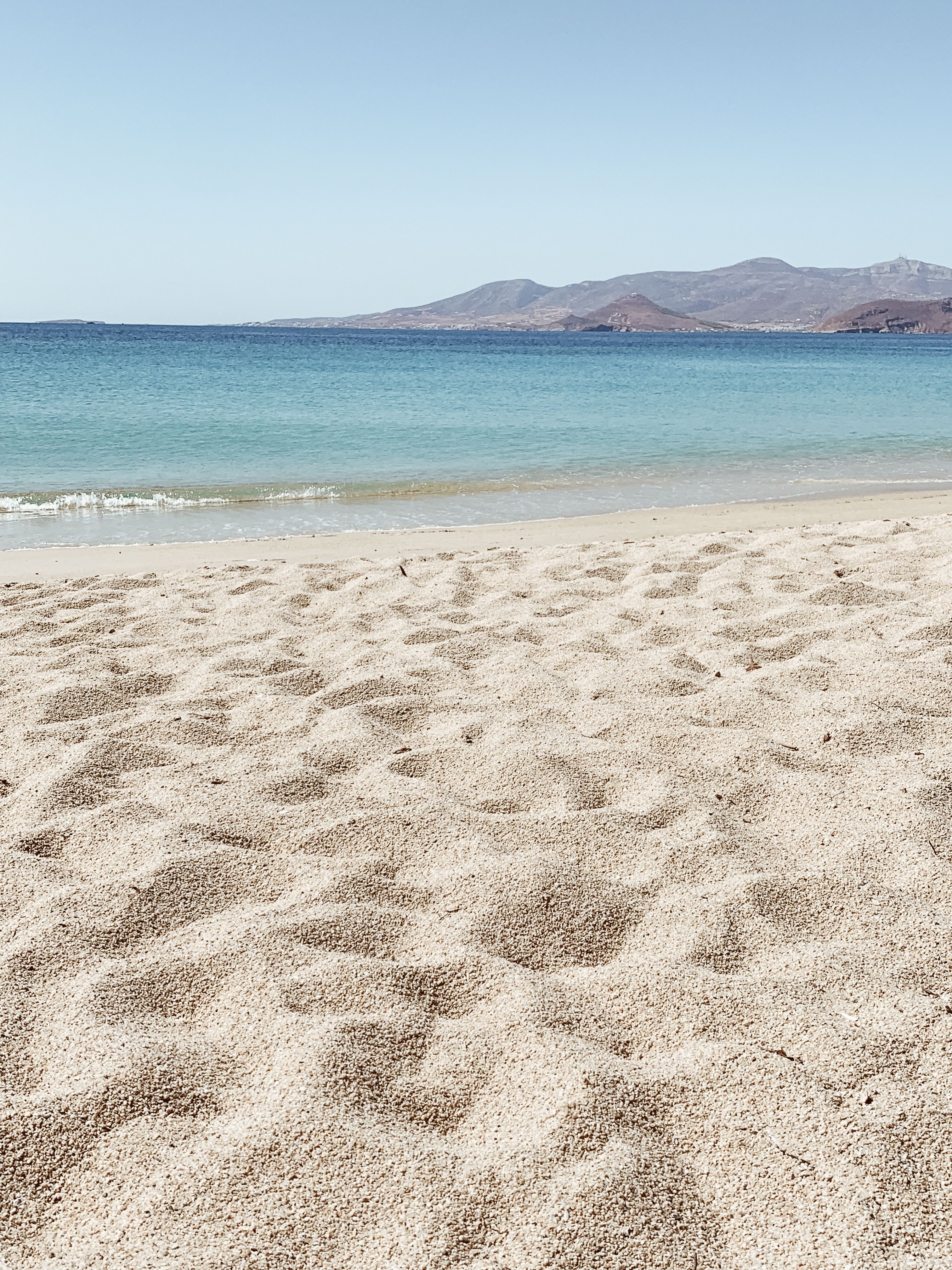 A relaxed Cycladic island scene — quiet beach or whitewashed village lane