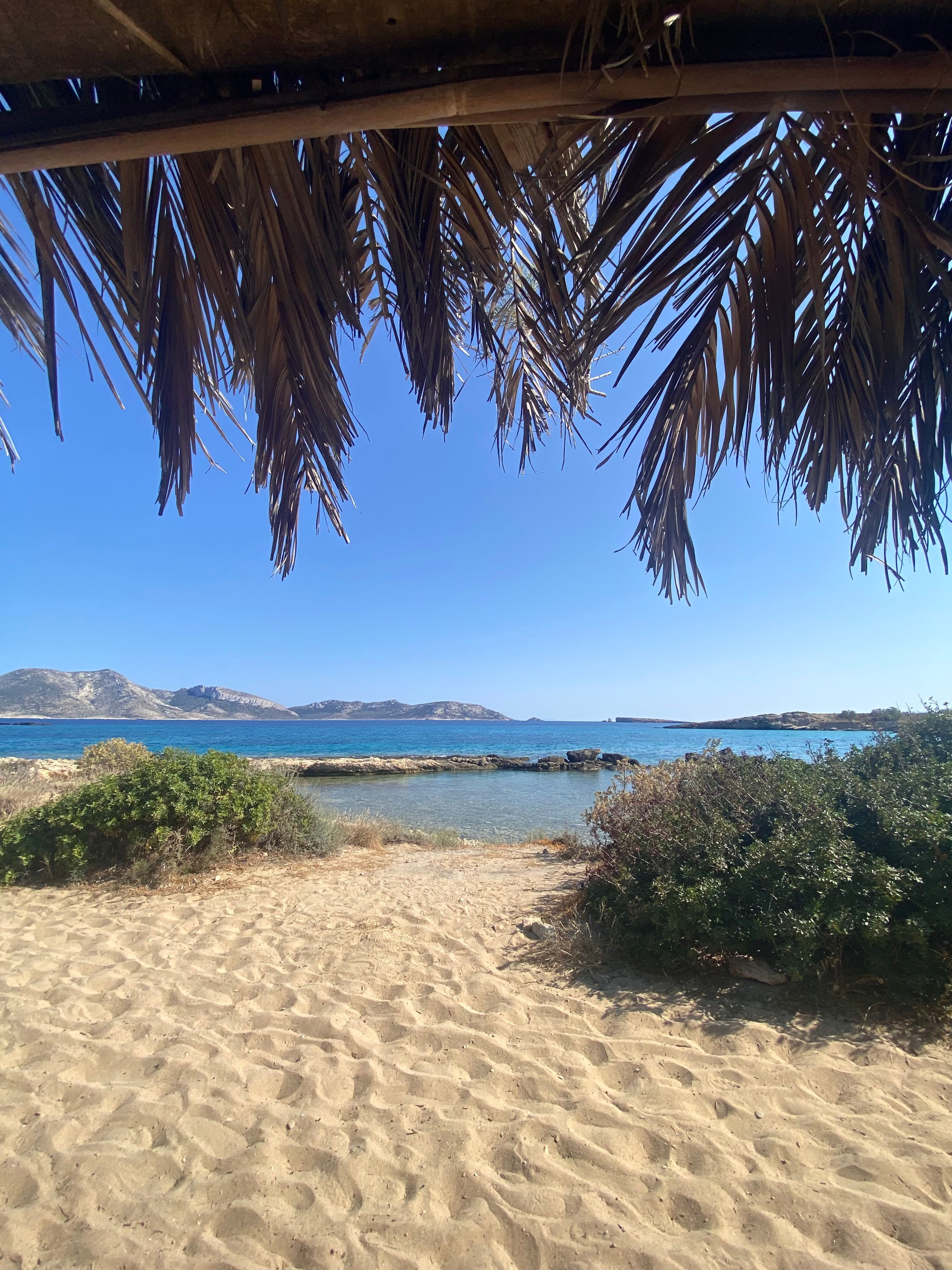 A calm, shallow, sandy Greek beach with families and gentle turquoise water
