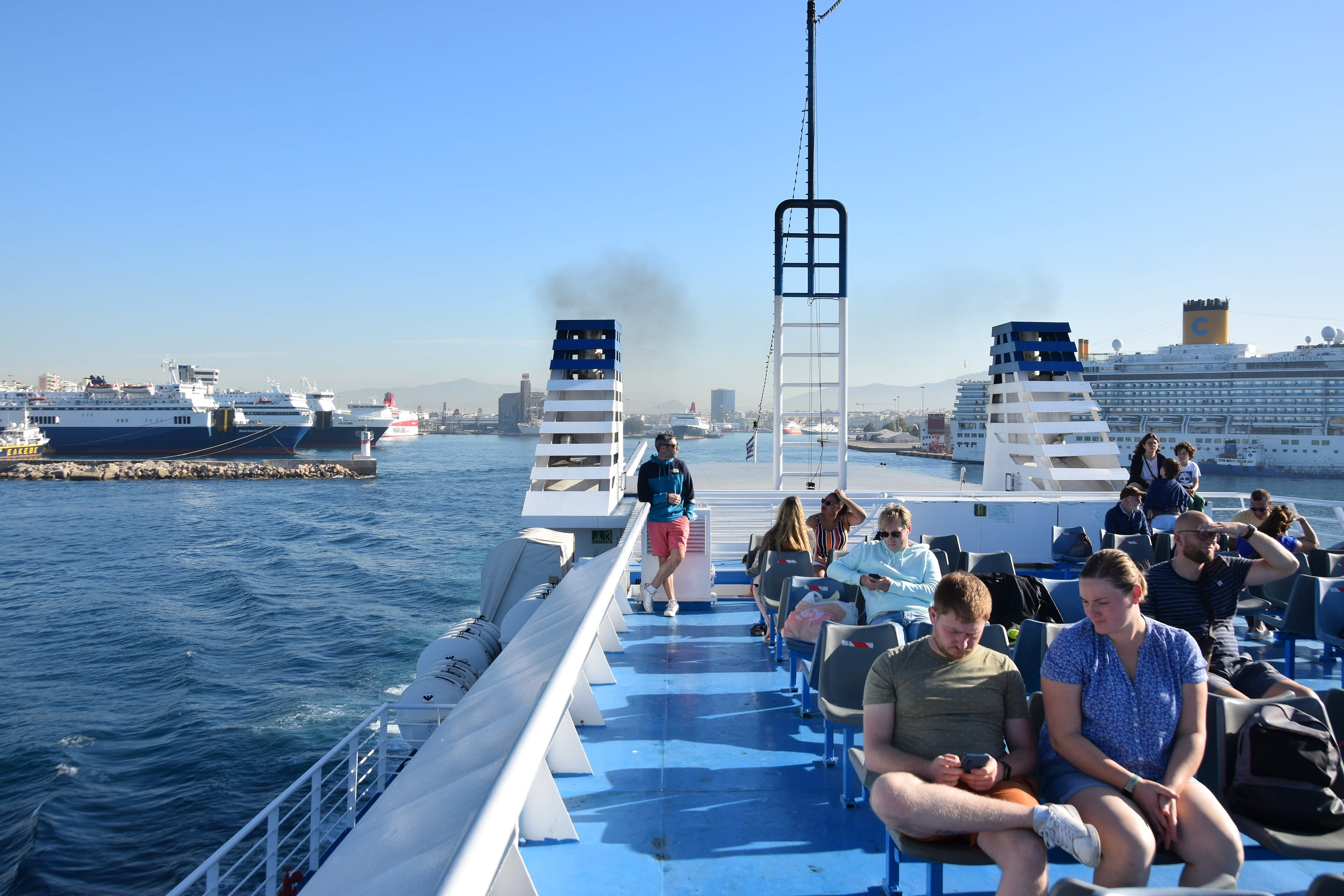 A ferry deck with passengers enjoying open-air views of the Aegean