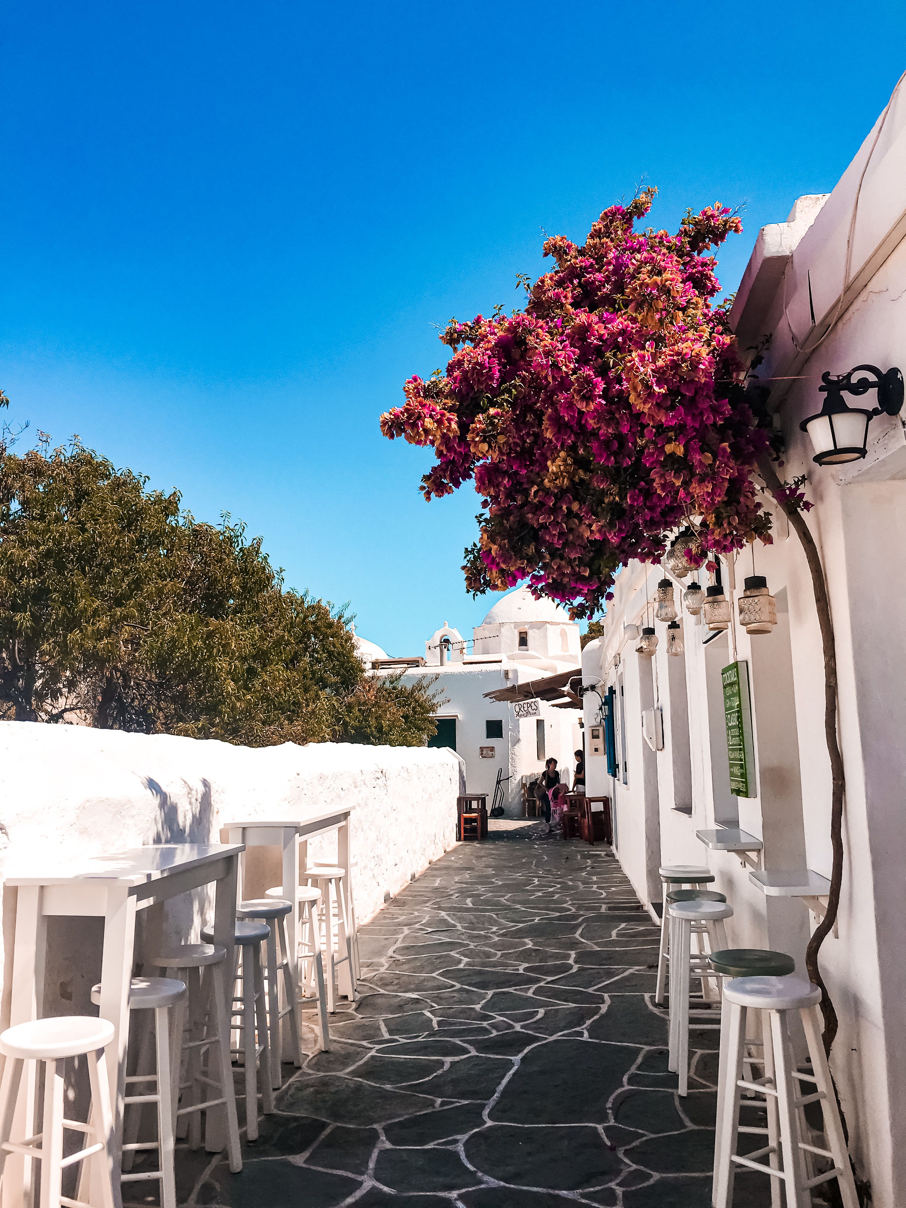 People relaxing at outdoor café tables in a sunny Greek square
